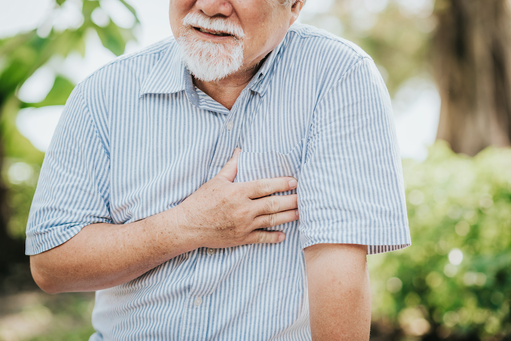 Cropped shot of senior man holding his chest and feeling pain suffering from heart attack outdoor at the park warning signs of heart failure - dr. mirza ashraf cardiology